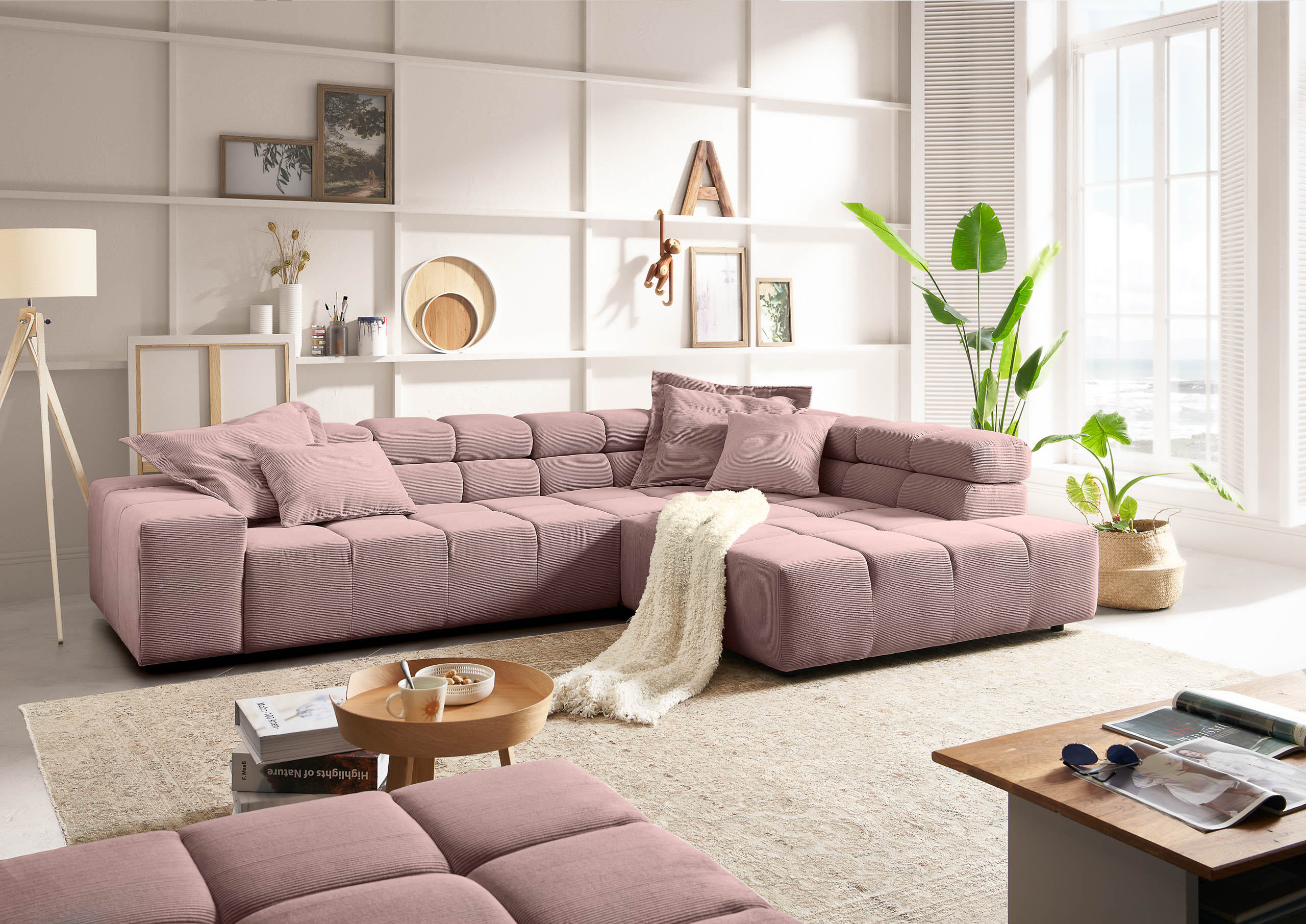 eine rosa feincord ecksofakastenförmig gesteppt steht an der weißen wand in einem hellen raum. beige teppich vor dem sofa