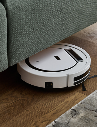 Bild zeigt einen Saugroboter, wie er unter das Bett fährt