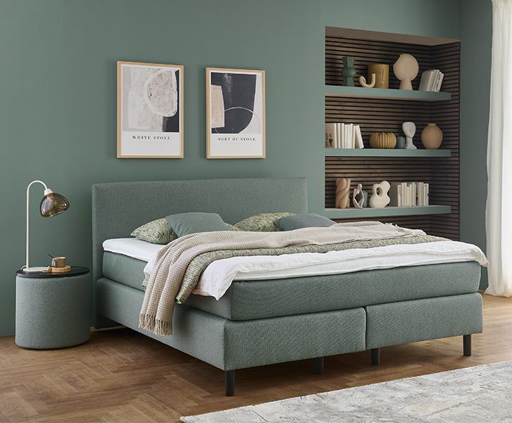 Bett in grün mit rundem Beistelltisch und Lampe